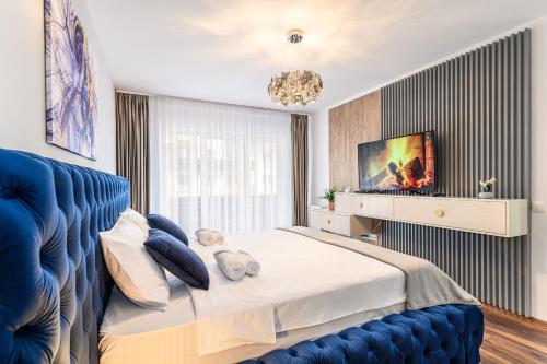 Schlafzimmer mit einem blauen Bett und einem TV in der Unterkunft High Comfort Brasov in Braşov