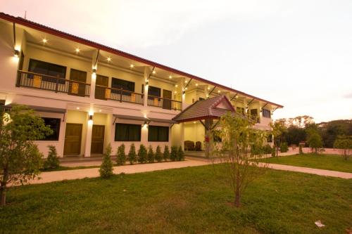 a large white building with a lawn in front of it at The Rise Resort in Sukhothai