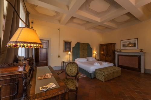 a bedroom with a bed and a table in a room at Palazzo Leopoldo Dimora Storica & Spa in Radda in Chianti