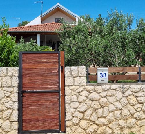 a wooden gate in front of a stone wall at Holiday House DA & DO in Pakoštane