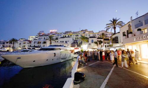 a group of people standing around a boat in a harbor at Deluxe 2 bedroom Golf Apartment Puerto Banus Marbella 12 Minutes Away by G00gIeMaps in Estepona