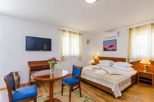 a bedroom with a bed and a table and a tv at Apartments & Rooms V&M in Dubrovnik