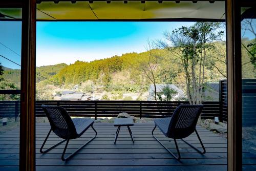 two chairs and a table on a porch with a view at 田篭の灯り in Ukiha