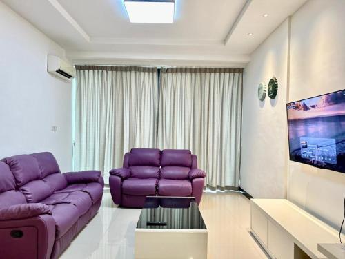 a living room with a purple couch and a tv at Jeff and Ricky Homestay 8 Boulevard Imperial Suites in Kuching