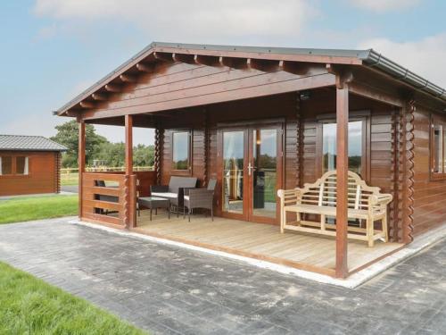 a wooden gazebo with a table and chairs at Ty Mai, Parc Y Fronwen in Newborough