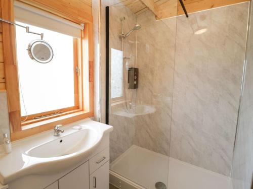 W łazience znajduje się prysznic, umywalka i lustro. w obiekcie Ty Mai, Parc Y Fronwen w mieście Newborough