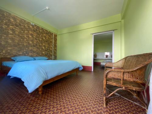 um quarto com uma cama, uma cadeira e um espelho em DPM HOMESTAY em Bomdila