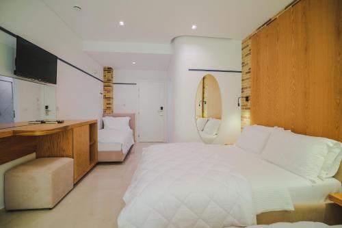 a bedroom with a large white bed and a desk at Hotel Piccolino in Sarandë