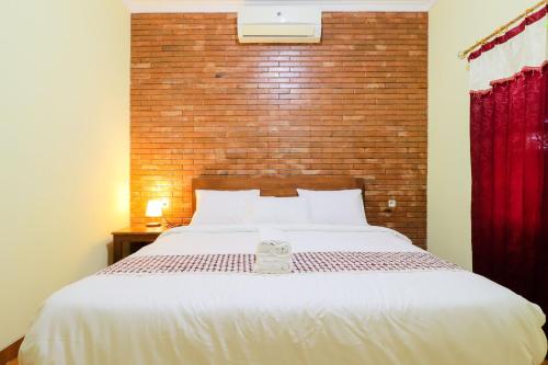 KembanglimusにあるHomestay Nike Bedのレンガの壁のベッドルーム1室(白い大型ベッド1台付)