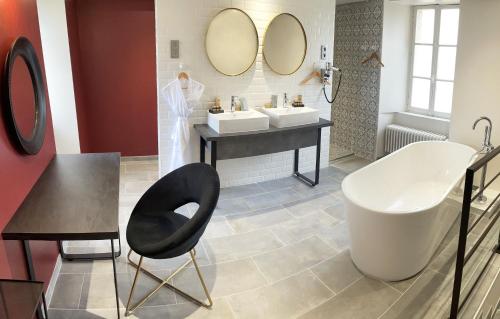 baño con 2 lavabos y silla negra en Château de Bernesq en Bernesq