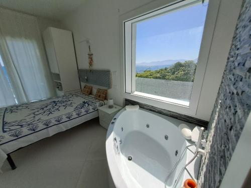 baño con bañera, cama y ventana en La Luna sul Mare, Sea-Luxury Rooms, en Casteldaccia