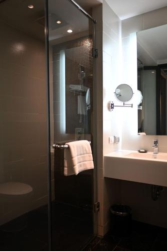 a bathroom with a shower and a sink and a mirror at Mövenpick Hotel Sukhumvit 15 Bangkok in Bangkok