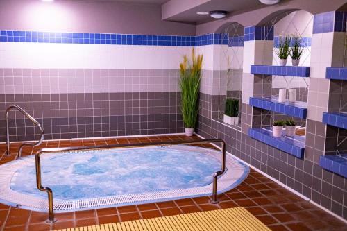 y baño con bañera de hidromasaje y azulejos azules. en Hotel Zátiší, en Špindlerův Mlýn