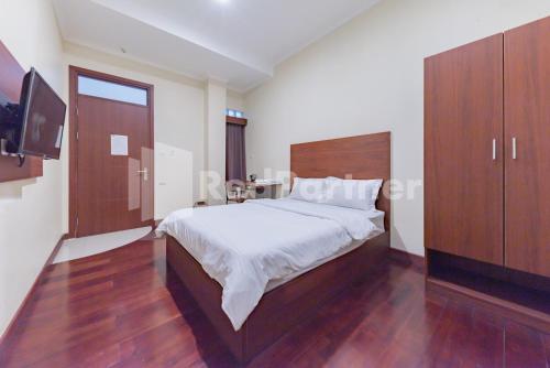 a bedroom with a large bed and a tv at Maleo Residence Bandung Mitra RedDoorz in Bandung
