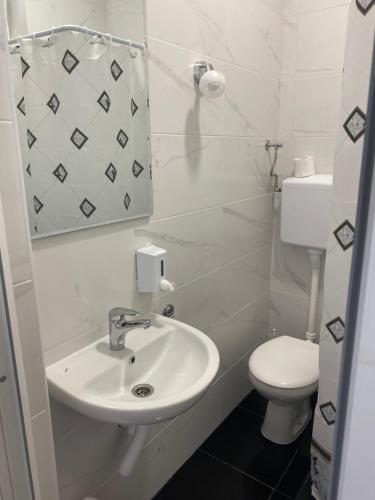 La salle de bains blanche est pourvue d'un lavabo et de toilettes. dans l'établissement LUX apartmani za izdavanje, à Bečej