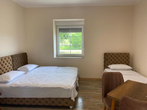 um quarto com 2 camas, uma mesa e uma janela em LUX apartmani za izdavanje em Bečej