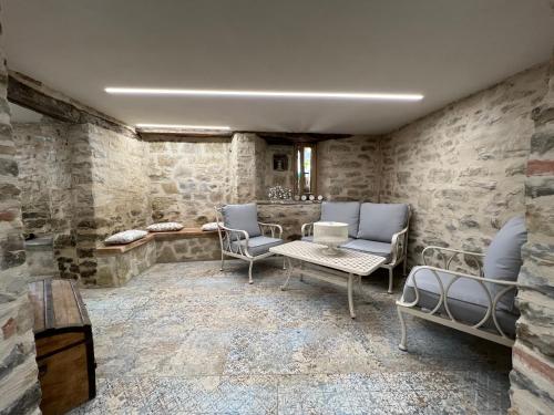 a room with stone walls and chairs and a table at Appartamenti Gli Ippocastani in San Benedetto Belbo