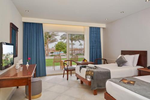 Three Corners Sea Beach Resort في خليج كورايا: غرفة فندقية بسريرين ومكتب وطاولة