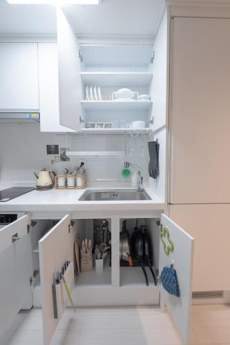 una cucina con mobili bianchi e un lavandino di Greenery SEOUL a Seul