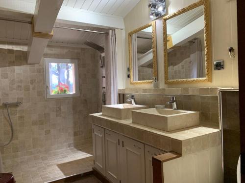une salle de bain avec deux lavabos et deux miroirs dans l'établissement Le Clos, à Courthézon