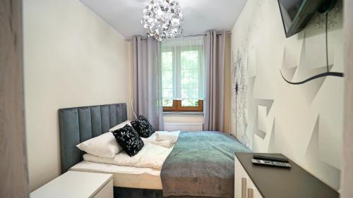 a small bedroom with a bed and a chandelier at Apartamenty EverySky - Nad Łomnicą 14A-B in Karpacz