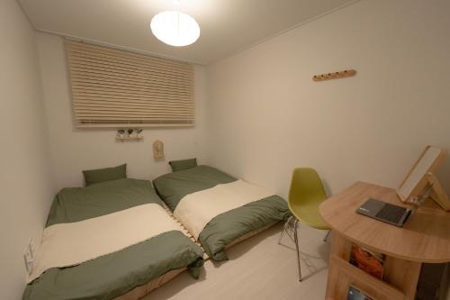 a bedroom with two beds and a desk and a table at Greenery SEOUL in Seoul