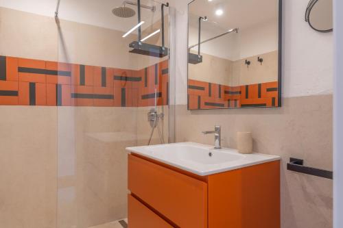 an orange and white bathroom with a sink and shower at Baja di Li Ranci by DomusAway in Baja Sardinia