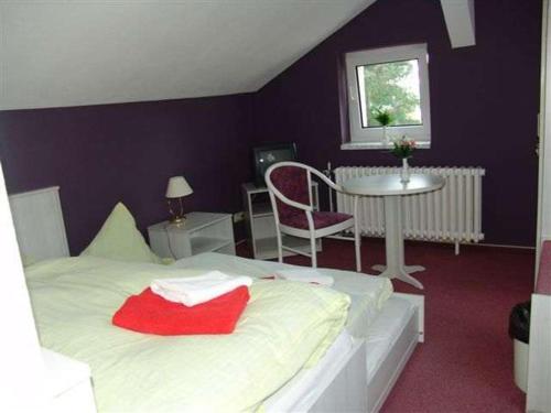 sypialnia z białym łóżkiem, stołem i oknem w obiekcie Hotel & Restaurant Märkische Schweiz w mieście Buckow