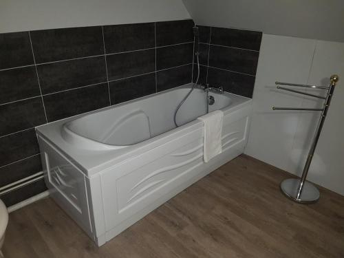 a white bath tub in a bathroom with black tiles at Maison Campagne Dix Kilomtres De in Hautot-lʼAuvray