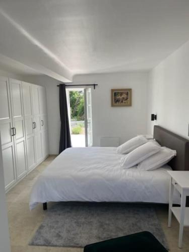 une chambre blanche avec un grand lit et une fenêtre dans l'établissement Le Clos de Russy, à Russy