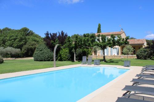 a swimming pool with chairs and a house in the background at Provence.bienvenue chez nous in Rognes