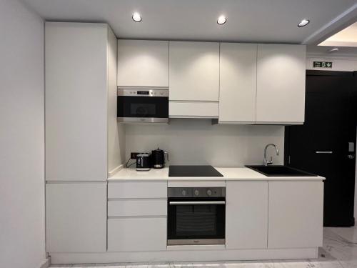 La cuisine est équipée de placards blancs et d'un four avec plaques de cuisson. dans l'établissement Msida Marina Apartments, à Msida
