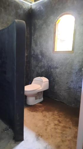 a bathroom with a toilet and a window at Rumah Nalu surf camp in Krui