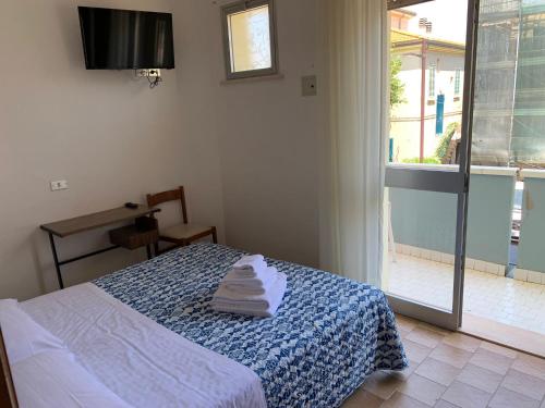 Hotel Estense في ريميني: غرفة نوم عليها سرير وفوط