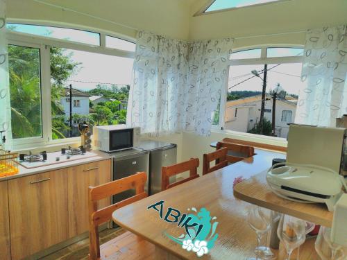 a kitchen and dining room with a table and windows at Maya-Abiki Mauritius in Albion