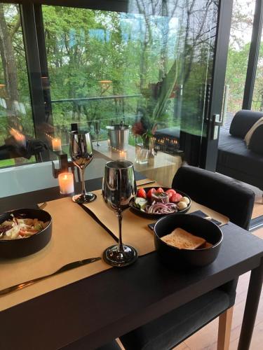 a table with two plates of food and wine glasses at ForRest Boutique Cabin in Dunabogdány