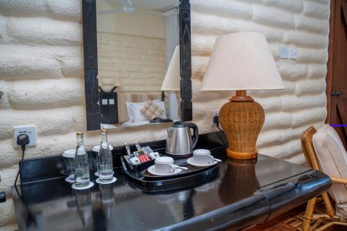 uma mesa com um candeeiro e um espelho num quarto em Taita Hills Safari Resort & Spa em Tsavo