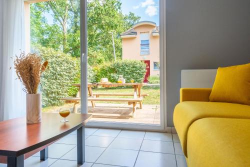 a living room with a yellow couch and a table at Comfort Aparthotel Nantes La Beaujoire in Nantes