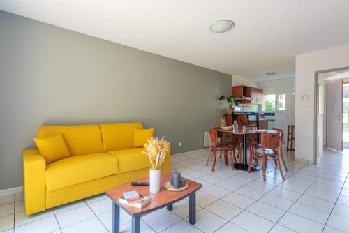 a living room with a yellow couch and a table at Comfort Aparthotel Nantes La Beaujoire in Nantes