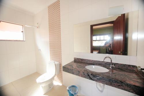een badkamer met een toilet, een wastafel en een spiegel bij Chacara c piscina e vista para Cach dos PretosSP in Joanópolis