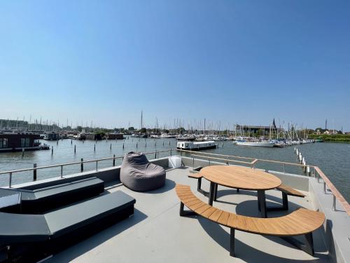 a boat deck with a table and benches and boats at Surla Houseboat "De Albatros" in Monnickendam Tender included in Monnickendam