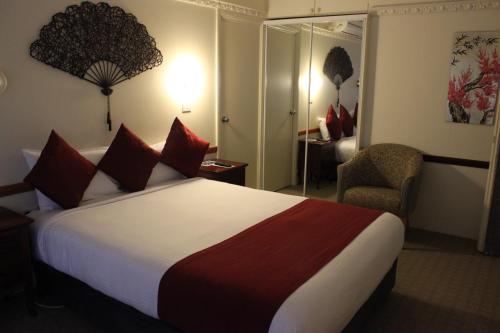 a hotel room with a large bed and a chair at Three Explorers Motel in Katoomba