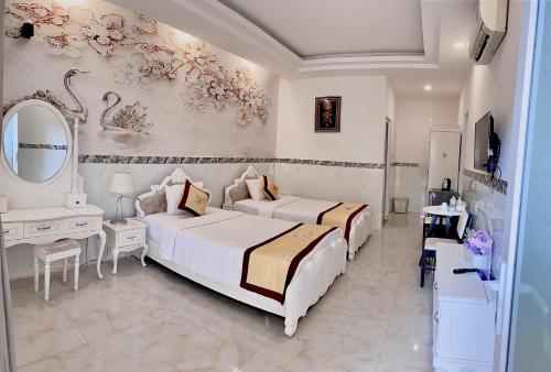 a bedroom with two beds and a vanity and a mirror at Godiva Villa Phu Quoc in Phu Quoc