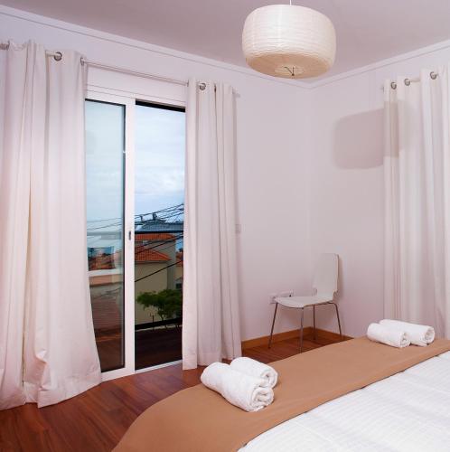 a bedroom with a bed and a large window at Carvalhal Old Town in Funchal