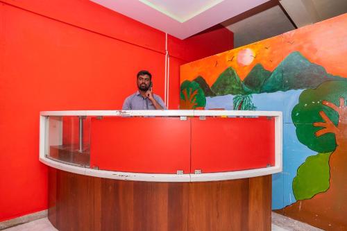 Un uomo in piedi dietro un podio in una stanza rossa di OYO Flagship 28067 Shree Stays a Bangalore