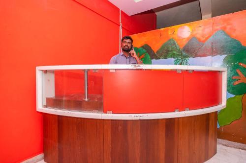 Un uomo in piedi dietro un bancone in una stanza di OYO Flagship 28067 Shree Stays a Bangalore