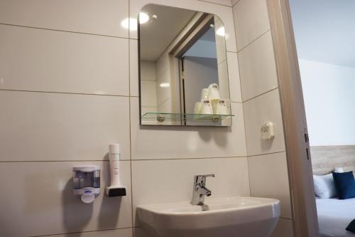 a bathroom with a sink and a mirror at Hôtel Lémand Lyon Est - Villefontaine in Villefontaine