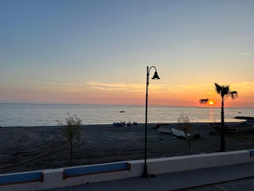 a street light on a beach with the sun setting at VistAmare - Fuscaldo in Marina di Fuscaldo