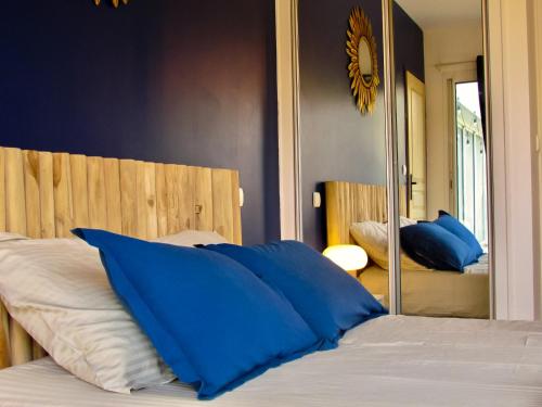 a bedroom with a bed with blue pillows and a mirror at Domaine du Haou - Grand gîte au cœur d'un domaine bucolique in Saint-Laurent-de-Gosse