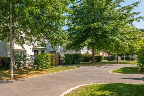 a driveway with trees in front of a building at Comfort Aparthotel Nantes La Beaujoire in Nantes